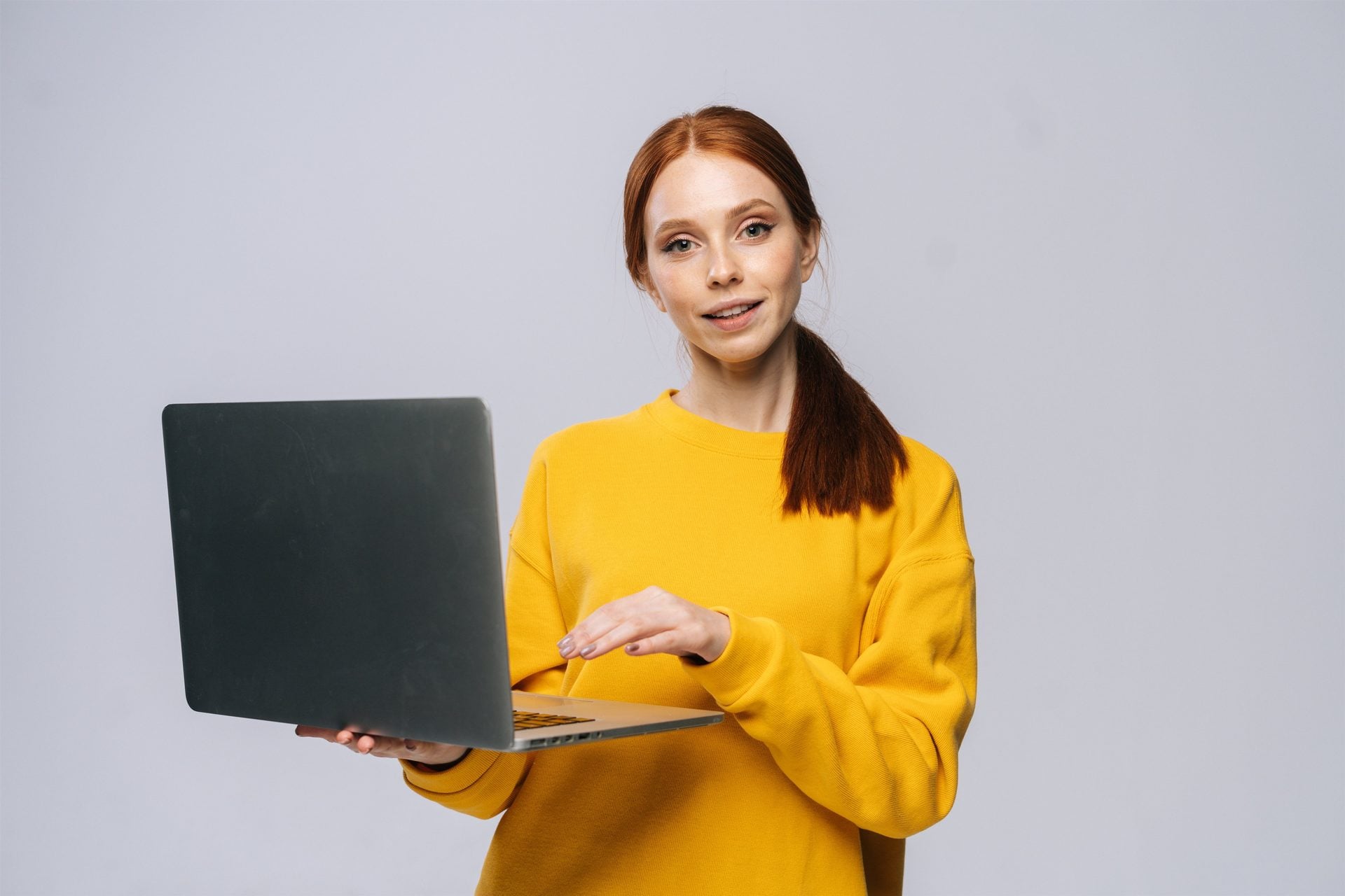 Woman in a yellow sweater presenting a laptop